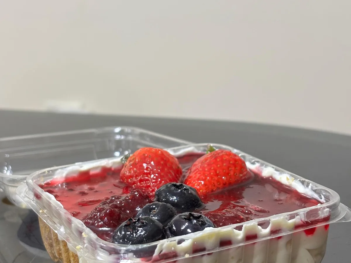 Cheesecake individual con frutos rojos en un envase transparente.
