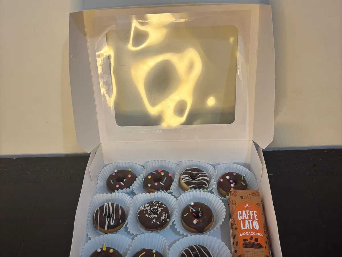 Caja abierta con minidonas decoradas y una bebida al costado.