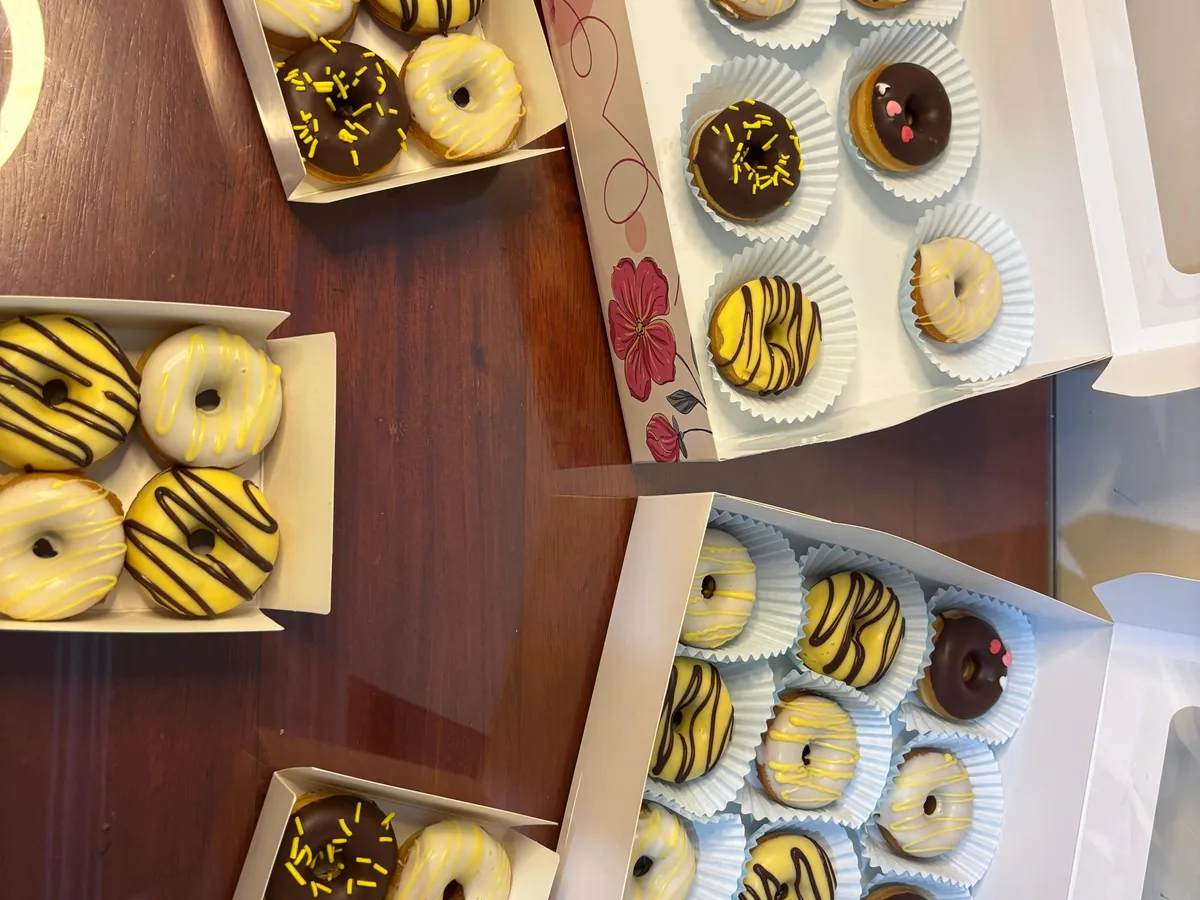 Varias cajas abiertas con minidonas decoradas en tonos amarillos y negros.
